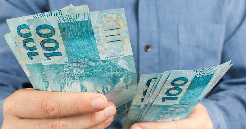 Pessoa segurando notas de 100