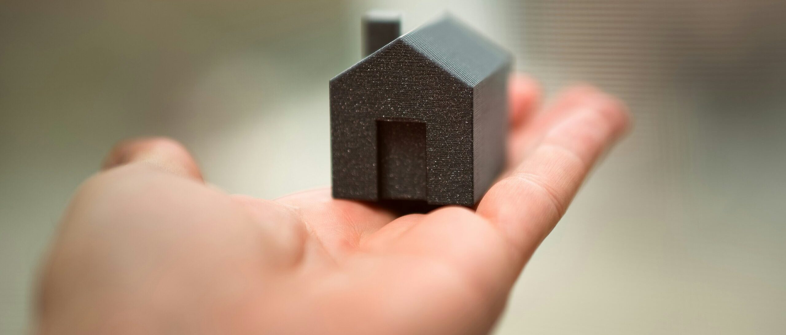 Miniatura de casa preta sobre a palma de uma mão