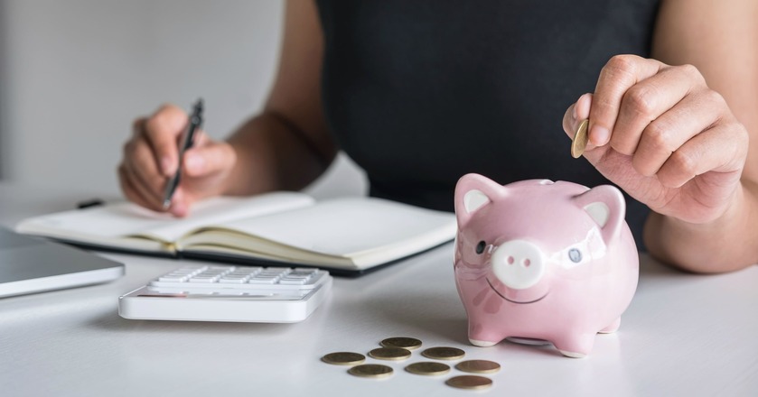 Pessoa guardando moedas num porquinho