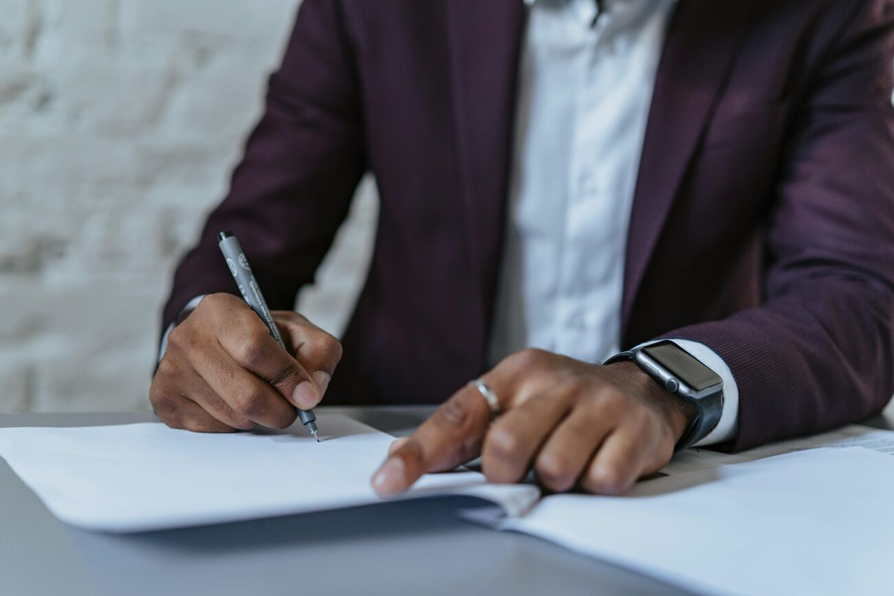 Homem escrevendo em um caderno com caneta